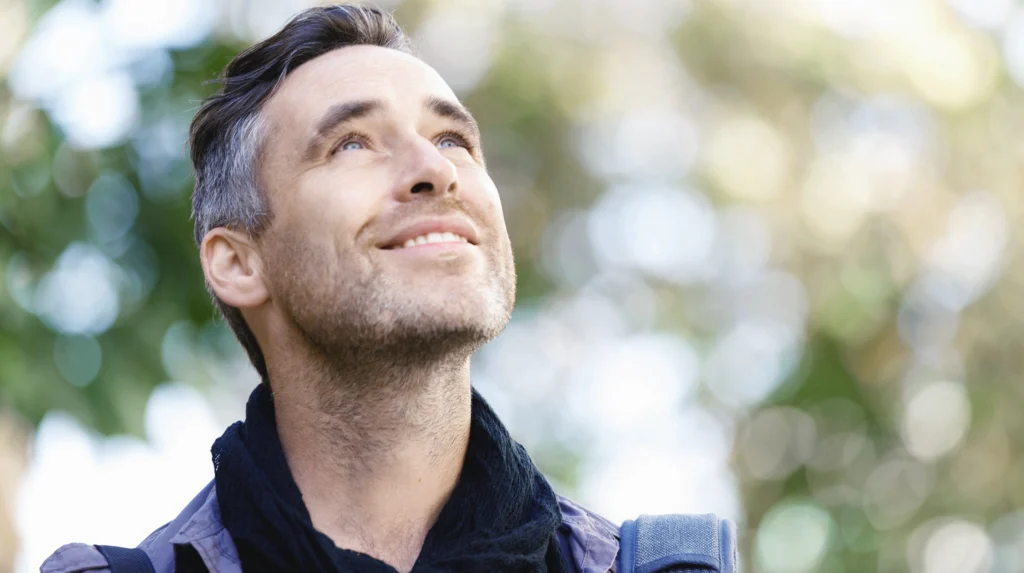 man standing outdoors in woodland, breathing in fresh air